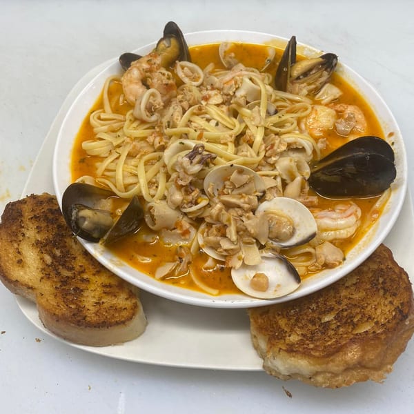 Seafood linguine with mussels, clams, shrimp, and calamari in a red sauce, served with garlic bread.