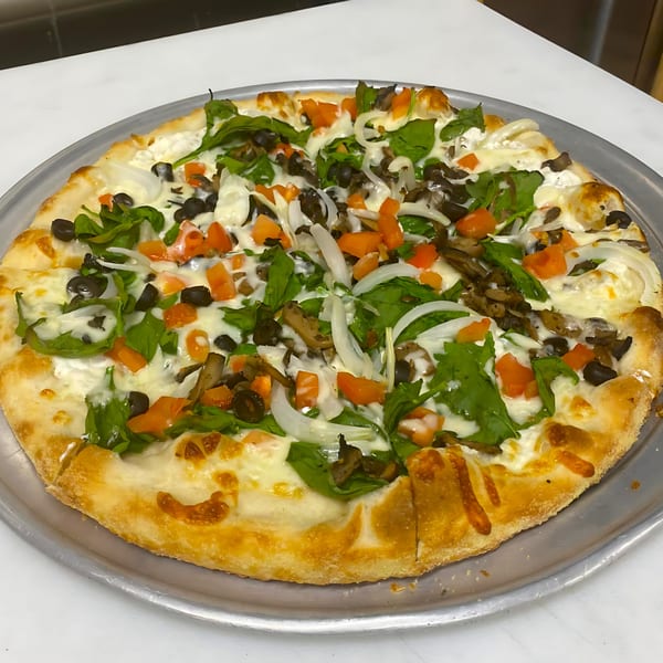 A Sals pizza with white sauce, spinach, mushrooms, black olives, diced tomatoes, and onions.