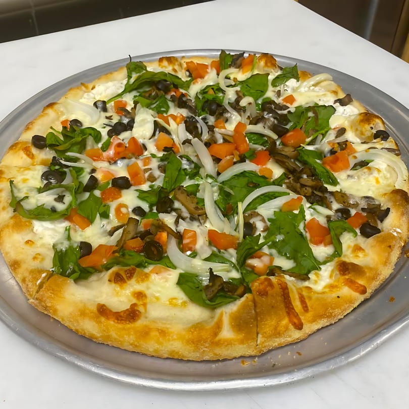 A Sals pizza with white sauce, spinach, mushrooms, black olives, diced tomatoes, and onions.