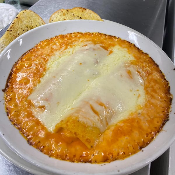 Baked manicotti with melted mozzarella cheese and tomato sauce, served with garlic bread.